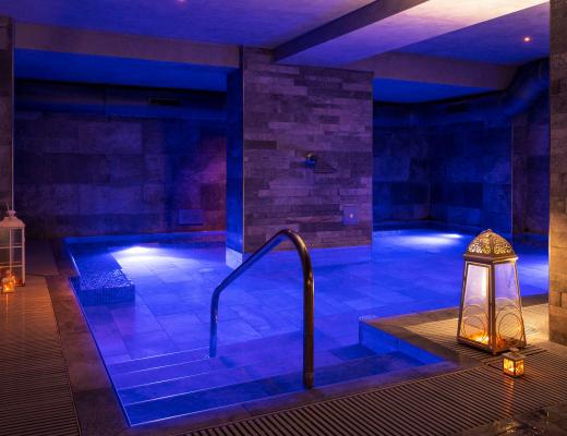 Piscina interna con illuminazione blu e lanterne decorative.