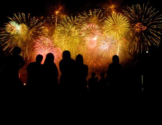 Persone che guardano fuochi d'artificio colorati nel cielo notturno.