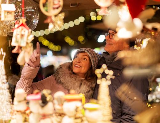 Coppia felice esplora un mercatino di Natale pieno di decorazioni.