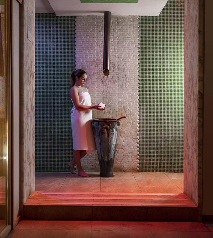 Donna in spa con asciugamano, vicino a sauna.