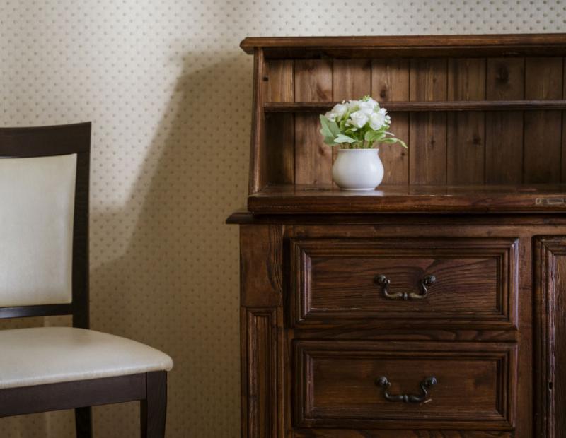 Sedia e mobile in legno con vaso di fiori bianchi.